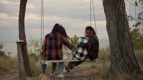 Two-couples-of-lovers-are-swinging-on-a-wooden-swing-and-hugging.-Rest-in-the-country-house-by-the-sea