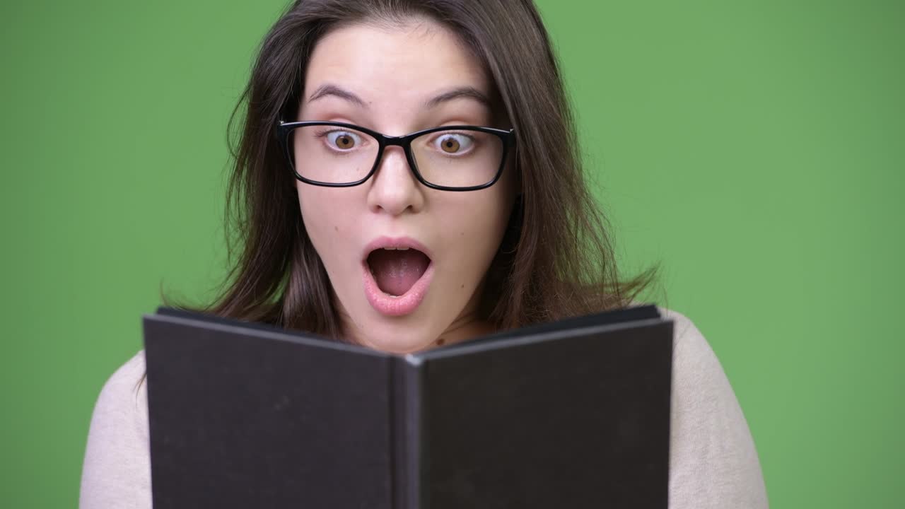Young beautiful woman looking shocked while studying