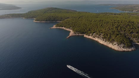aerial panning shot of a high speed boat cruising along the coastline of brac island, croatia, navigating between hvar and milna over the adriatic sea