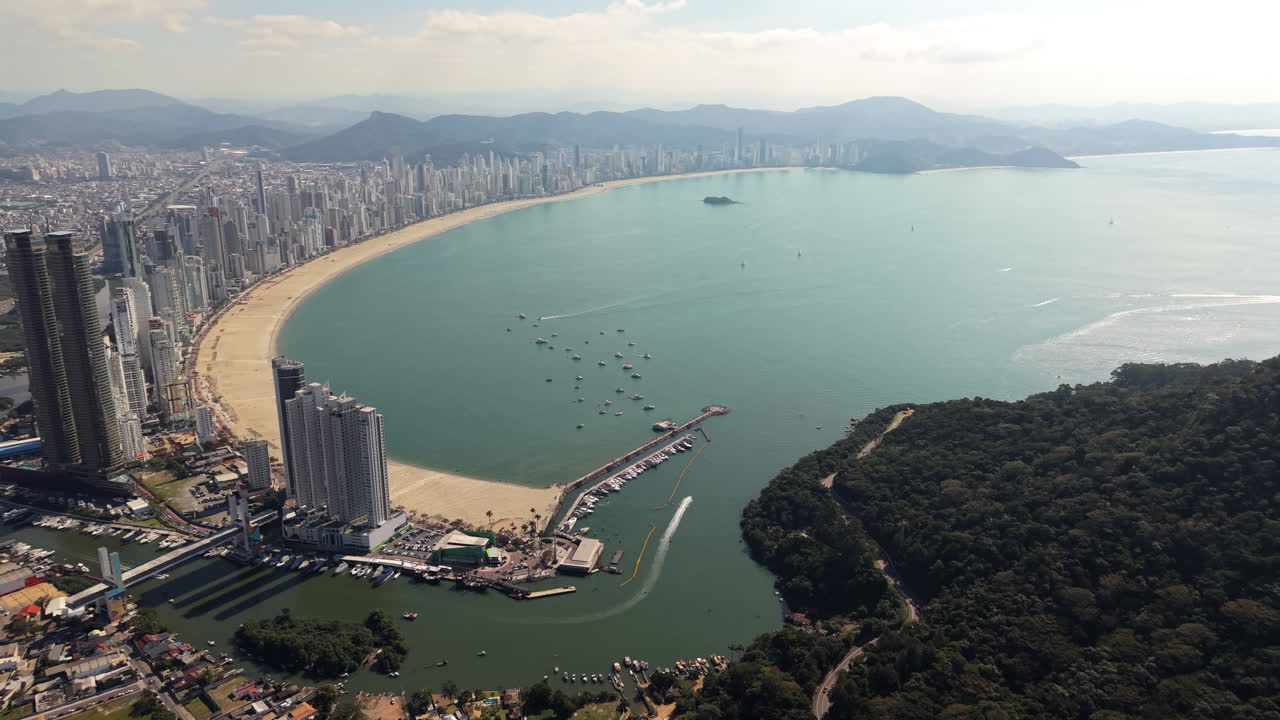 A sweeping drone view highlights Balneario Camboriu's expansive coastline, Marina Tedesco, Ilha das Cabras, and iconic skyline including Yachthouse Towers, One Tower, and Infinity Coast Tower