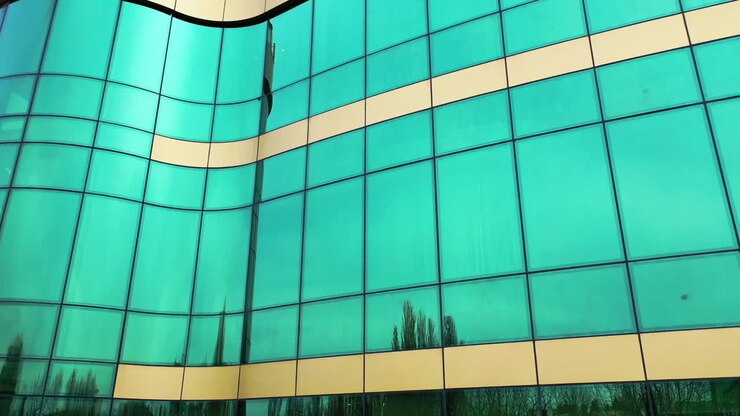 Ripresa aerea delle finestre di un moderno edificio per uffici che riflettono il paesaggio urbano in una giornata di sole. La vita reale della città si riflette nelle finestre a specchio di un edificio per uffici.