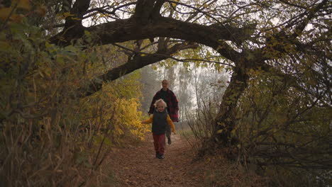 el niño alegre corre en el bosque de otoño y la madre lo sigue entretenimiento feliz y diversión en el fin de semana familiar