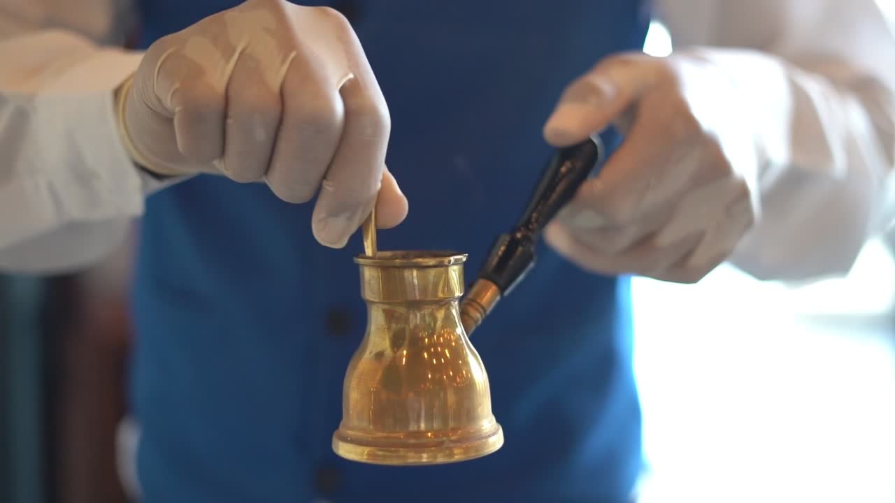 A man stirs coffee on a pot, close up shot, insert shot