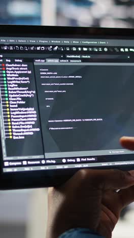 vertical video close up of data center software developer checking code on tablet