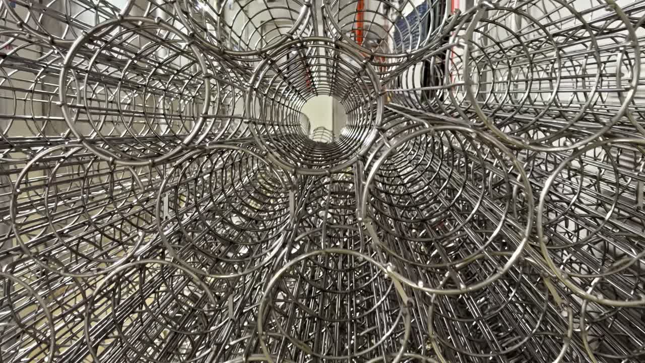 Symmetri af cylindriske metaltrådsrammer til industrielle støvopsamlingssystemer på fabrikslager.