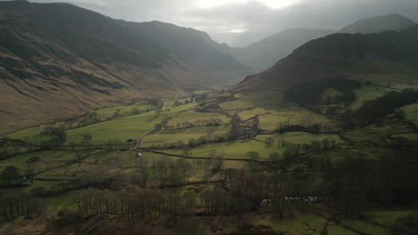 Flying-over-patchwork-fields-and-reveal-of-hidden-valley-with-misty-mountains-in-English-Lake-District-UK