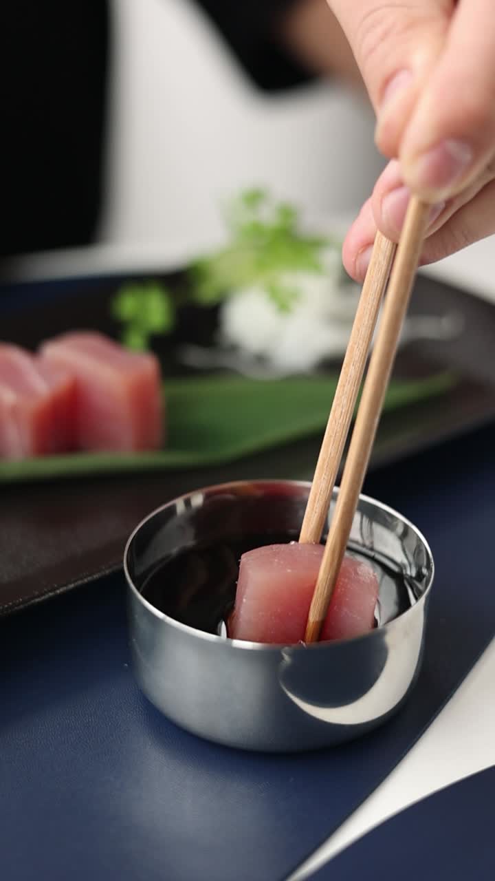 comiendo sashimi de atún con palillos