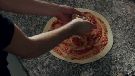 anonymous man adding cheese to pizza