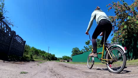 young woman riding vintage bicycle along a rural road in a village