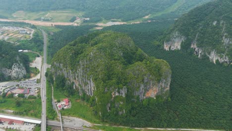 aerial view of kelantan, malaysia, featuring dramatic limestone hills surrounded by vast palm oil plantations, blending natural rock formations with cultivated landscapes