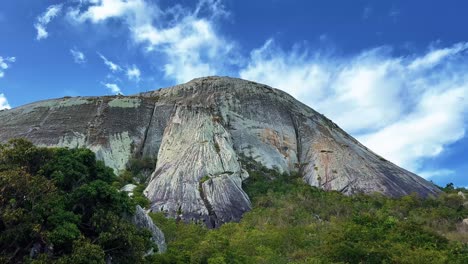 Tilt-up-shot-of-the-giant-Pedra-de-Sao-Pedro-mountain-in-Sítio-Novo,-Brazil-in-the-state-of-Rio-Grande-do-Norte-from-the-base-looking-up-on-a-sunny-warm-summer-day