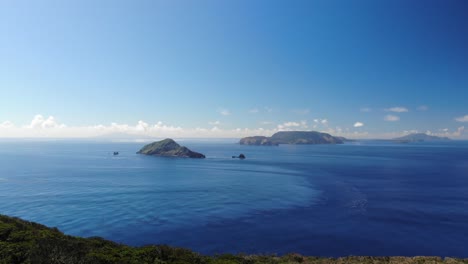 Forwards-aerial-drone-flight-over-island-towards-beautiful-islands-in-blue-ocean-on-clear-day