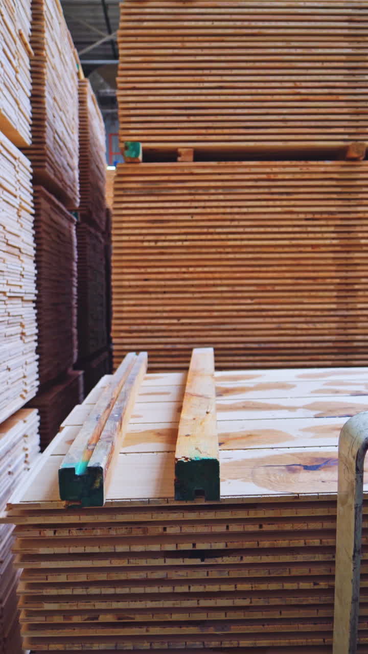 Wooden boards for flooring in the factory. Forklift cart putting pile of parquet panels inside the warehouse. Production of furniture. Vertical video