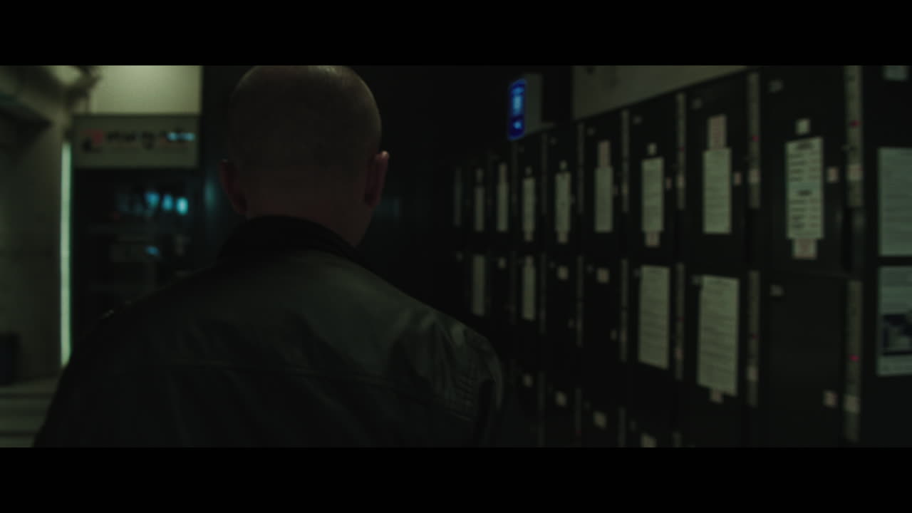 A bald dangerous looking man opens train station locker