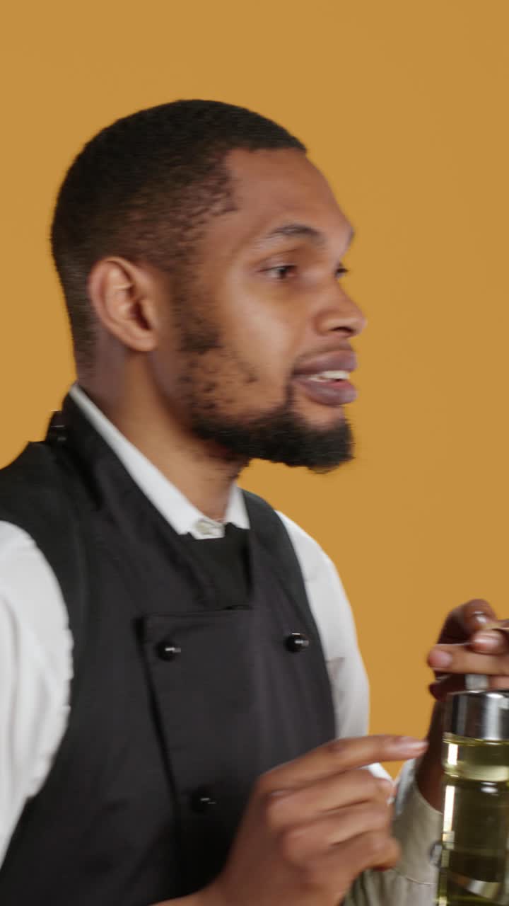 Barman afroamericano che gesticola e parla con uno shaker da cocktail