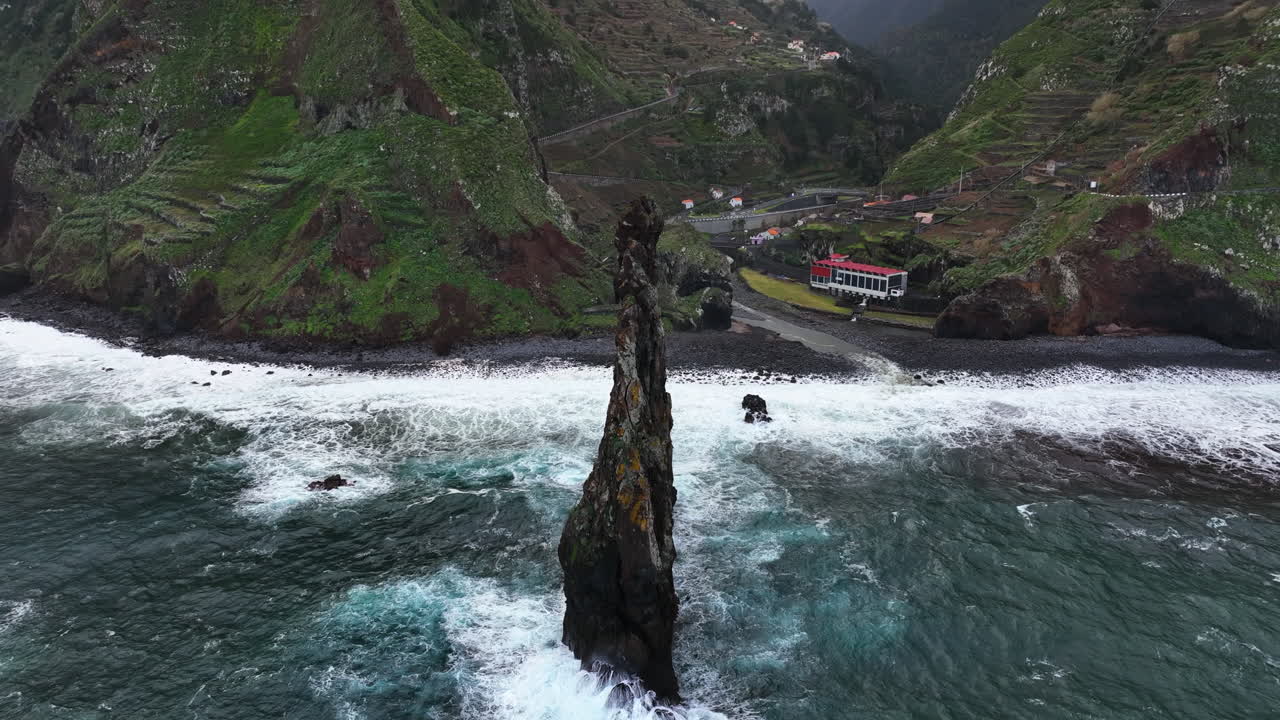 Drone tilting away from the Ilheus da Rib, in cloudy Ribeira da Janela, Madeira