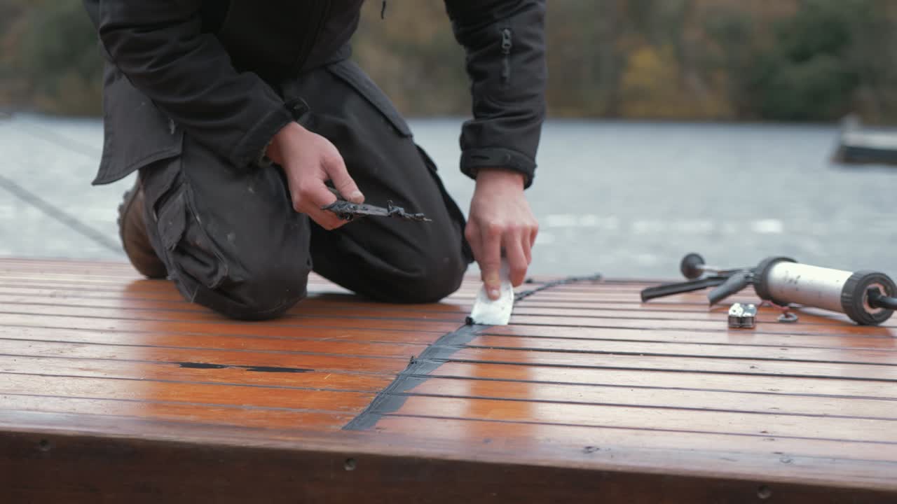 마스틱 방수 실란트로 누수를 막는 보트의 선실 지붕을 수리하는 목수