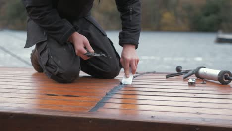 carpenter repairing cabin roof of boat sealing leaks with mastic waterproof sealant