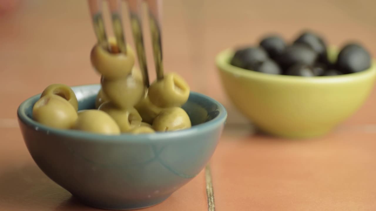 Snacking on green olives with fork close up shot