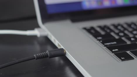 plugging in aux jack cable into modern laptop computer, close up view