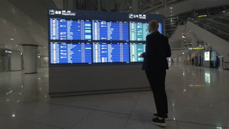 Mujer-Con-Almohadilla-Mirando-El-Horario-De-Vuelo