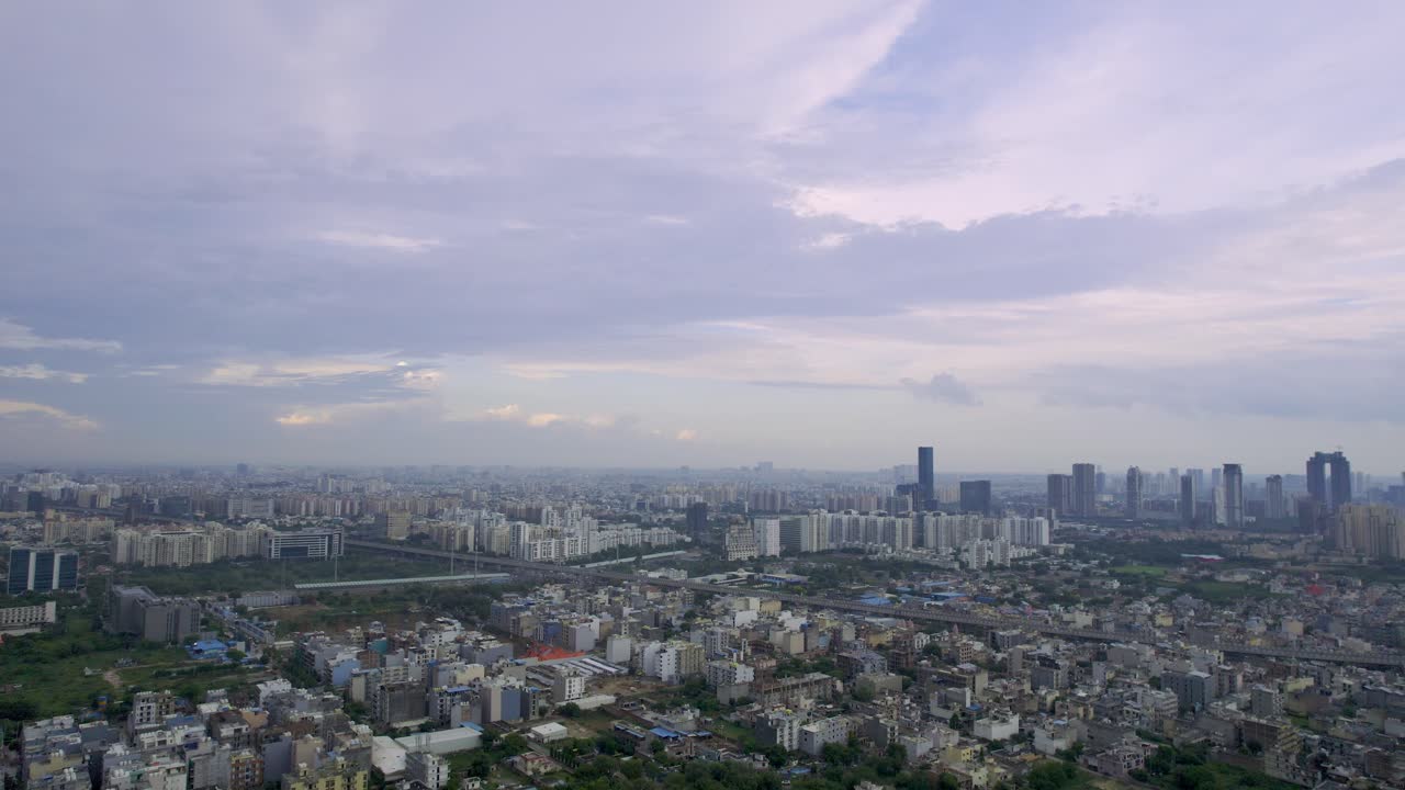 Panning up reveal shot from drone showing small single floor densely packed houses on the rural outskirts and the huge skyscrapers in the city center of Delhi, Bangalore, Hyderabad, India