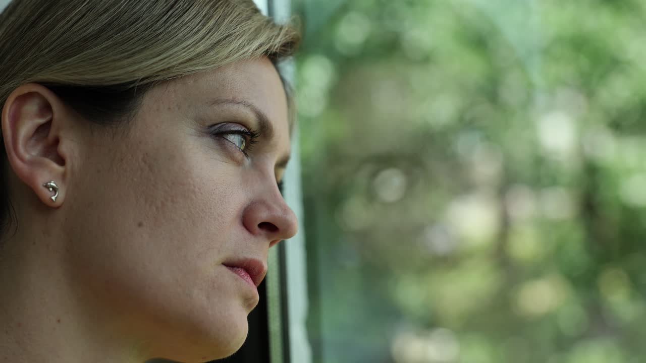 A woman looking out the window with a pensive expression
