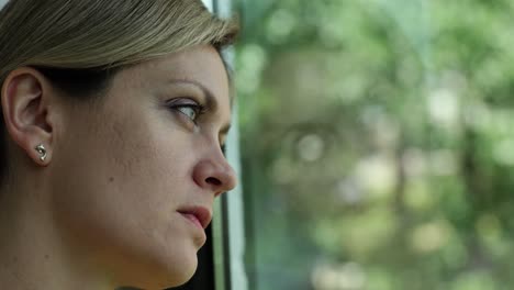 A woman looking out the window with a pensive expression