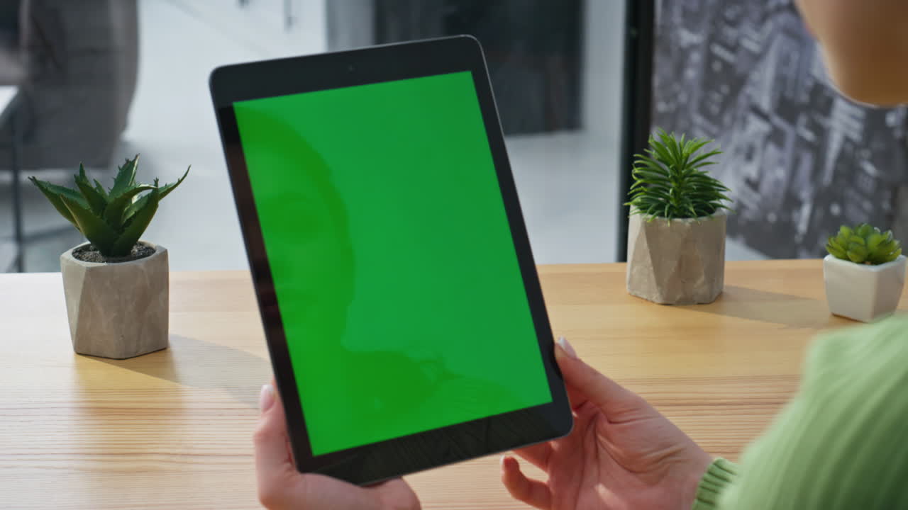 Closeup hands holding mockup tablet in light office. Woman watching tab screen