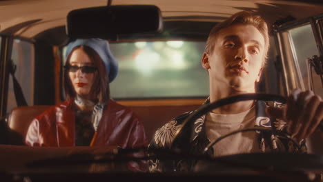 driver talking with stylish female passenger in vintage taxi cab at night