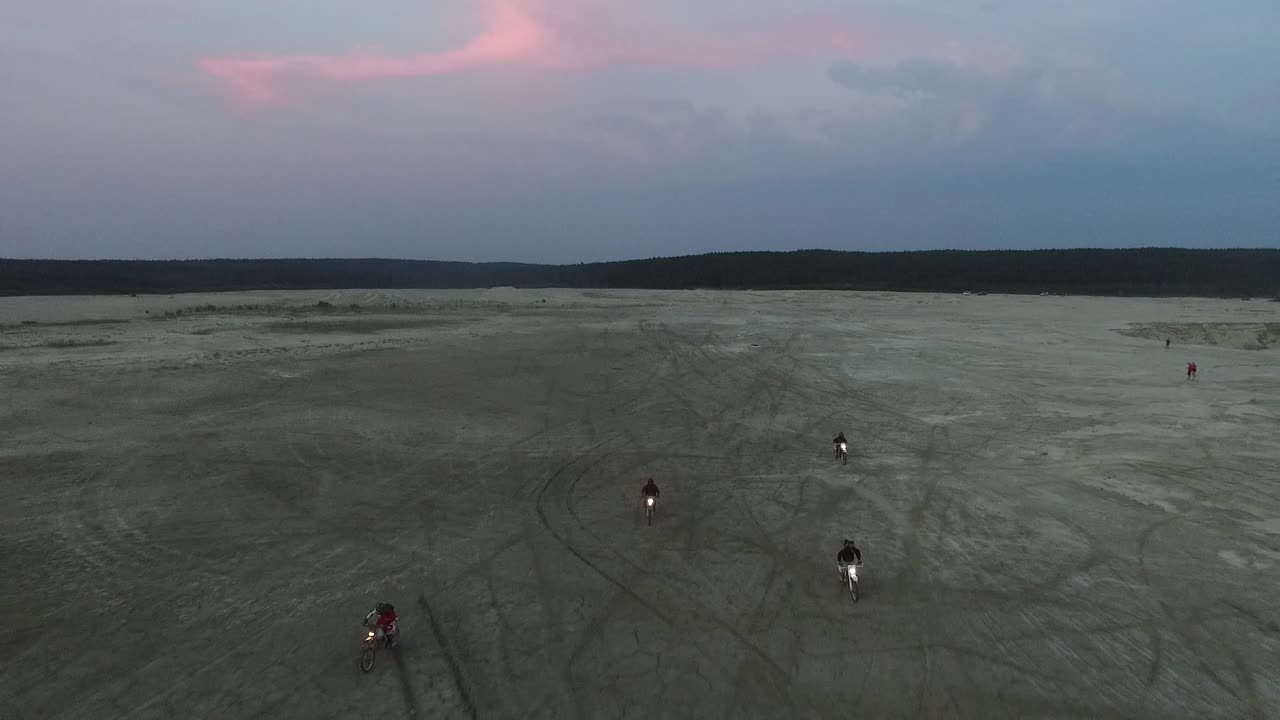 motociclistas montando a través de dunas de arena al anochecer
