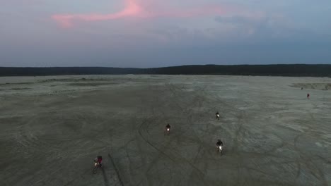 motorcyclists riding through sand dunes at dusk