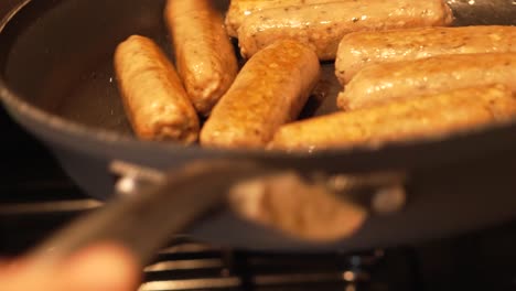 sausages being cooked and shaken in frying pan by chef