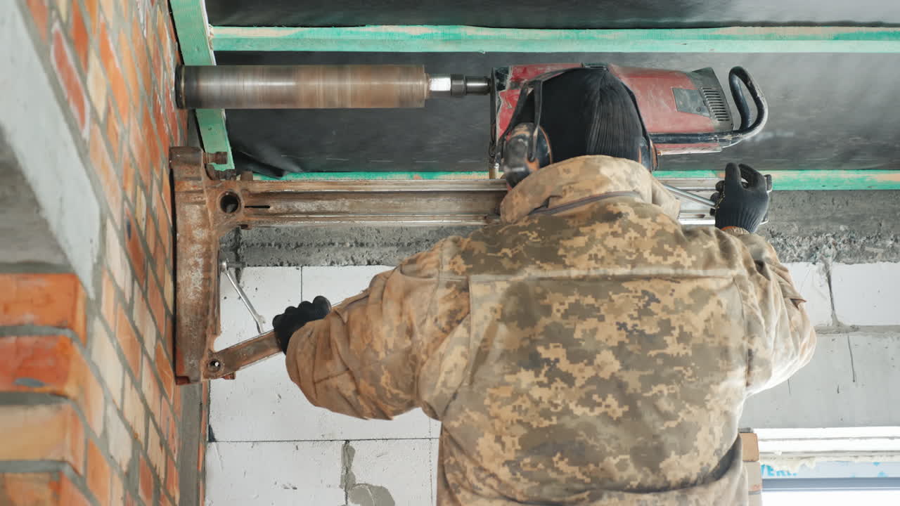 trabajador perfora una pared con una poderosa herramienta eléctrica hace agujeros para establecer comunicaciones