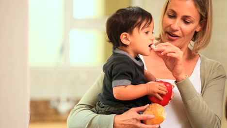 Baby-In-Den-Armen-Der-Mutter-Hält-Eine-Rote-Paprika-Und-Isst-Brot