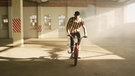 bmx rider in an empty warehouse using smoke grenade