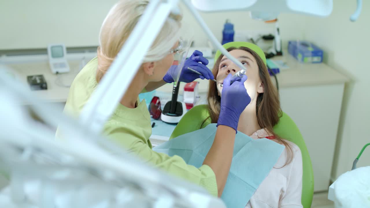 Kadın hastanın çürük dişini delen diş hekimi. Stomatolog dental matkap kullanıyor.