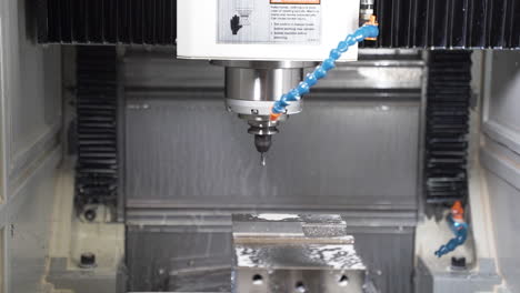 máquina cnc automática que comienza a perforar, enfriada por un fluido de corte