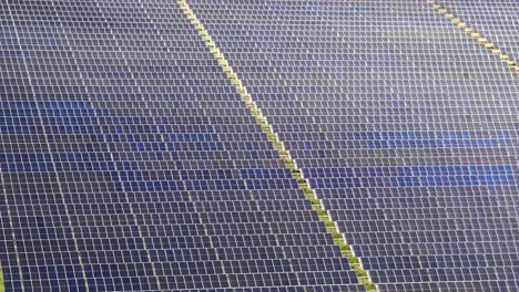 drone glides above large solar farm, revealing photovoltaic panels in bright, natural daylight