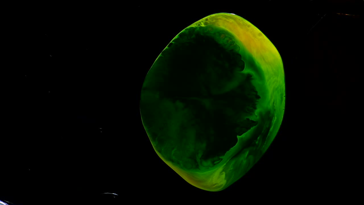 un orbe ahuecado de color amarillo y verde, bañado en luz, pulsa en la oscuridad más allá: un videoclip abstracto totalmente natural