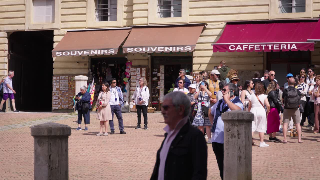 Stabilized shot of many people walking on a street surrounded by old buildings in Tuscany, Italy, on a cloudy day. Slow moition