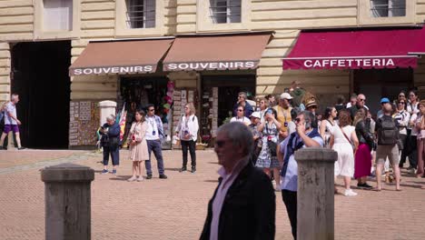 stabilized shot of many people walking on a street surrounded by old buildings in tuscany, italy, on a cloudy day. slow moition
