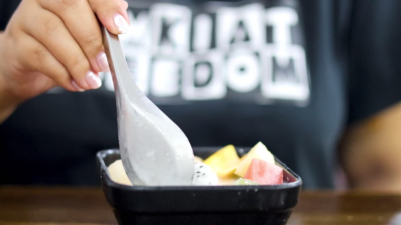 다채로운 과일 디저트를 먹는 사람