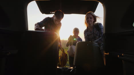 the family with the child is going on a trip together they put the bags in the trunk of the carr