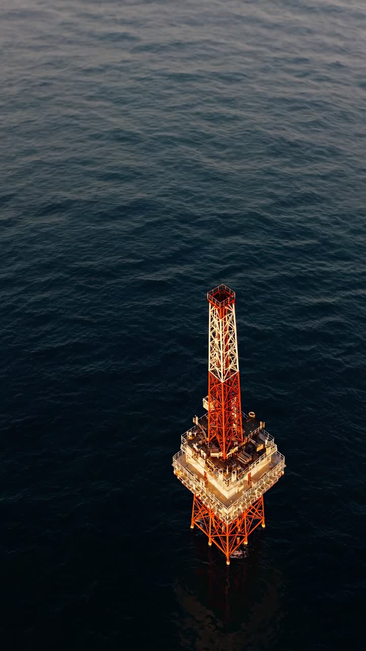Luftfoto af en offshore olieplatform i havet ved solnedgang