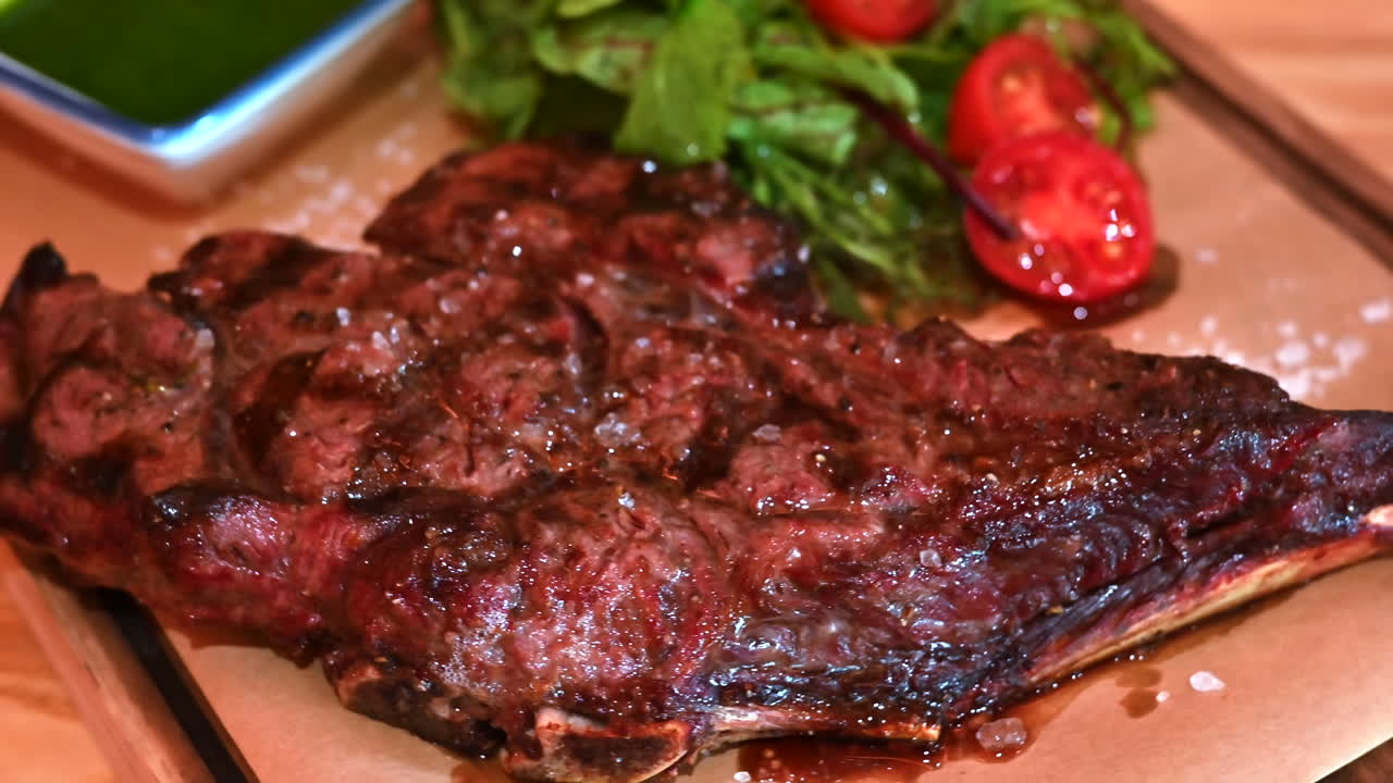 Big ribeye stake on a wooden plate with vegetables