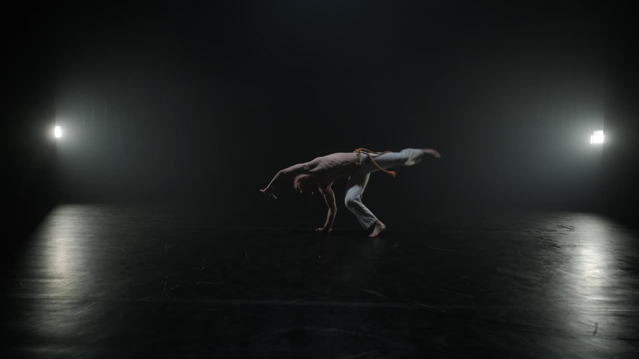 Lottatori di Capoeira che eseguono mosse dinamiche sul palco. Arti marziali, danza e acrobazie in azione. Atleti a torso nudo che mostrano forza, flessibilità e tecnica sotto i riflettori