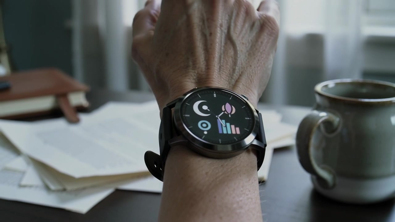 Raising bare forearm, watch-wearing senior checking watch for activity data at home desk