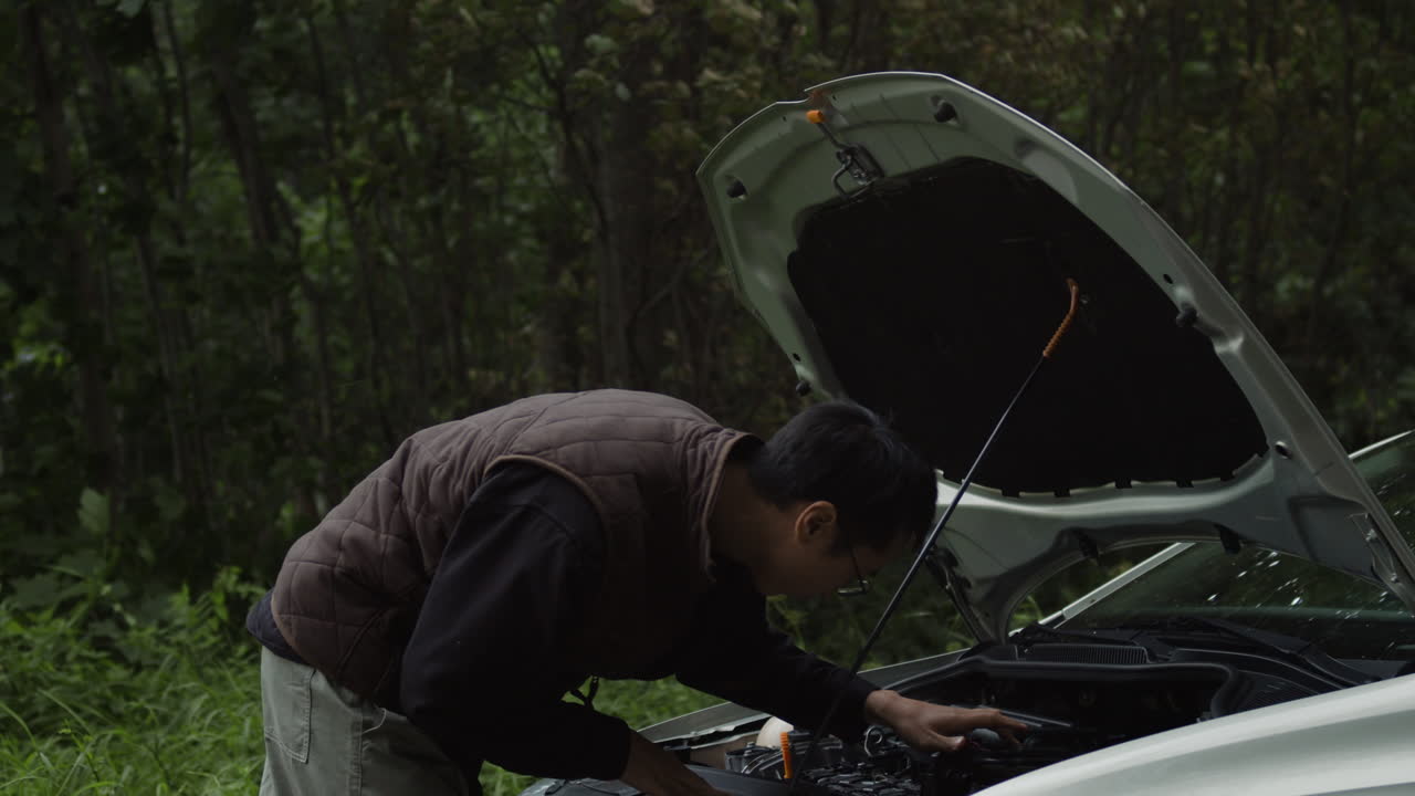 Man repairing car engine outdoors