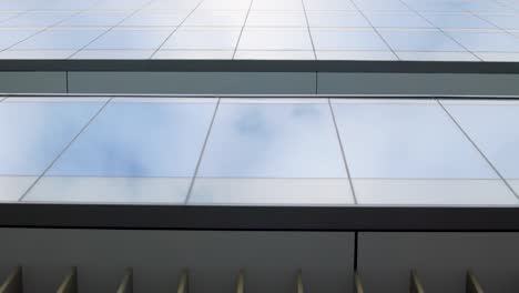 looking up at modern glass office building with reflective curtain wall and large glass window panels